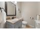 Cozy powder room featuring a granite countertop, a decorative mirror, and a single sink vanity at 10500 Pacific Palisades Ave, Las Vegas, NV 89144