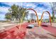 Park swing set with vibrant colors and soft ground, surrounded by mature trees at 314 Meadow Brush Pl, Henderson, NV 89011