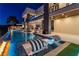 Night view of the modern home exterior, showcasing the lit pool and stylish poolside furniture at 3266 S Spring Mountain Blvd, Pahrump, NV 89048