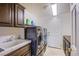 Well-lit laundry room with a sink, cabinetry, washer, dryer, and a white door leading outside at 4372 Melrose Abbey Pl, Las Vegas, NV 89141