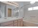 Bright bathroom featuring double sinks, a large mirror, and a tiled bathtub with shower at 5784 Dew Mist Ln, Las Vegas, NV 89110
