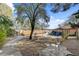 Large backyard with a concrete walkway, rock landscaping, and mature trees for shade at 5785 N Tee Pee Ln, Las Vegas, NV 89149