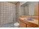 Bathroom with tiled walls, toilet, shower, mirror and sink with wooden cabinet at 5785 N Tee Pee Ln, Las Vegas, NV 89149