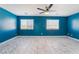 Spacious bedroom with blue walls, ceiling fan, and ample natural light from two windows at 6345 Strongbow Dr, Las Vegas, NV 89156