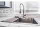 Close-up of a kitchen sink and window, featuring an elegant marble countertop and backsplash at 6345 Strongbow Dr, Las Vegas, NV 89156