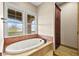 A relaxing bathtub with jets, a view from two windows and a wooden cabinet nearby at 14 Camino Barcelona Pl, Henderson, NV 89011