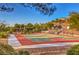 Outdoor basketball court with multiple hoops, perimeter landscaping, and hillside homes in the distance at 1532 Via Cassia, Henderson, NV 89052