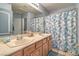 Well-lit bathroom featuring double sinks, framed mirrors, and a blue and white patterned shower curtain at 1532 Via Cassia, Henderson, NV 89052