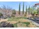 Backyard featuring a grassy area, tall, thin trees, and a small seating area on stone pavers at 1800 Montvale Ct, Las Vegas, NV 89134