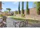 Backyard featuring a stone paver patio with grill and seating, a lawn area, and tall landscaping at 1800 Montvale Ct, Las Vegas, NV 89134