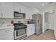 Modern kitchen with stainless steel appliances, white cabinets, and open access to the laundry area at 1800 Montvale Ct, Las Vegas, NV 89134