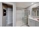 Clean bathroom with a glass-enclosed shower, white vanity with a mirror, and storage shelves in the adjacent closet at 2844 Alenga St, Henderson, NV 89044