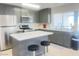 Well-lit kitchen with stainless steel appliances, quartz countertop island, and gray cabinets at 4194 Greenpoint St, Las Vegas, NV 89147