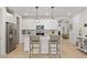 Bright kitchen features white cabinets, stainless steel appliances, island with bar seating and modern pendant lighting at 4743 S Sungold St, Pahrump, NV 89061