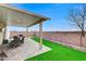 Covered patio features a dining area, artificial turf, and block wall surround at 4977 Vacaville Ave, Las Vegas, NV 89139