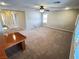 Spacious living room featuring neutral carpet, ceiling fan, access to stairway, and attached wooden table at 5361 Candlespice Way, Las Vegas, NV 89135