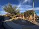 Scenic street view showcasing community entrance, landscaping, and tree-lined sidewalks with street signs on a sunny day at 5361 Candlespice Way, Las Vegas, NV 89135
