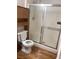 Full bathroom with a sliding shower door and a toilet with wooden storage cabinets at 5710 E Tropicana Ave # 2003, Las Vegas, NV 89122