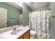 A bathroom with a single sink vanity, a shower curtain with a palm tree design, and neutral tile floors at 6472 Chebec St, North Las Vegas, NV 89084