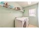 Functional laundry room with modern washer and dryer, shelving for storage, and a window at 6472 Chebec St, North Las Vegas, NV 89084