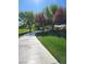 Concrete path winding through lush green grass with beautiful trees and a bright blue sky above, offering a serene outdoor experience at 6472 Chebec St, North Las Vegas, NV 89084