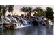 Stunning waterfall with water cascading over rocks into a serene pond, surrounded by lush greenery and palm trees at 6472 Chebec St, North Las Vegas, NV 89084