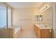 Bright bathroom featuring double sinks, a bathtub with tile surround, and a glass shower enclosure at 7317 Caballo Range Ave, Las Vegas, NV 89179
