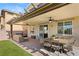 Inviting covered back patio with ceiling fans, dining area, outdoor seating and artificial turf at 7717 Rosebark Cliffs St, North Las Vegas, NV 89084
