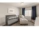 Cozy Bedroom with a gray crib, comfortable chair, and soft natural lighting at 7717 Rosebark Cliffs St, North Las Vegas, NV 89084