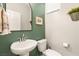 Stylish powder room featuring a pedestal sink, toilet, mirror, and decor at 7717 Rosebark Cliffs St, North Las Vegas, NV 89084
