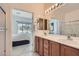 Bathroom featuring double sinks, wood cabinetry, a large mirror and view of the bedroom at 7921 Fantail Dr, North Las Vegas, NV 89084