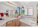 Bathroom with tile counters, tub and shower with glass door, large windows, and decor at 8432 Squaw Valley Ave, Las Vegas, NV 89128