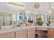 Bright bathroom featuring dual sinks, tile counters, and large mirrors with decorative plants at 8432 Squaw Valley Ave, Las Vegas, NV 89128