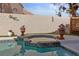 The hot tub and waterfall are viewed from the pool with a backyard privacy wall behind at 8432 Squaw Valley Ave, Las Vegas, NV 89128