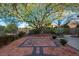 Backyard showcasing patio area with brick pavers, desert landscaping, and a mature tree at 10534 Mandarino Ave, Las Vegas, NV 89135