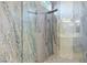 A modern shower with a multi-function shower head and grey stone-look walls at 10534 Mandarino Ave, Las Vegas, NV 89135