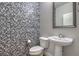 Stylish half-bathroom featuring a unique tiled wall and pedestal sink at 1056 Via Panfilo Ave, Henderson, NV 89011