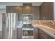 Close-up of the kitchen with stone countertops, stainless steel appliances, and modern backsplash at 1056 Via Panfilo Ave, Henderson, NV 89011