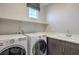 Functional laundry room with washer, dryer, utility sink, and counter space at 1056 Via Panfilo Ave, Henderson, NV 89011