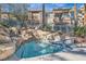 Inviting community pool featuring a rock waterfall, adjacent to modern condo buildings in a lush, serene setting at 10800 Amber Ridge Dr # 103, Las Vegas, NV 89144