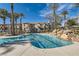 A beautiful community pool features rock waterfall feature and mature palm trees offering a resort-like atmosphere at 10800 Amber Ridge Dr # 103, Las Vegas, NV 89144