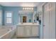 Well-lit bathroom with a tub, double sink vanity, and a view into the walk-in closet at 112 Austin Rose Ave, Henderson, NV 89002