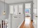 Hallway with white railing overlooking stairs, hardwood flooring, and a view of a bedroom through glass doors at 2020 Rainbow View St, Henderson, NV 89012