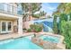 Backyard pool and hot tub area with mature landscaping, adjacent to a covered patio at 2020 Rainbow View St, Henderson, NV 89012