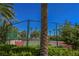 Community tennis court with mature landscaping and green fencing on a bright sunny day at 2050 W Warm Springs Rd # 4322, Henderson, NV 89014