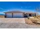 Desert home featuring a large driveway, two car garage and tidy landscaping at 3050 Oakridge Ave, Pahrump, NV 89048