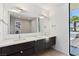 Modern bathroom featuring a double vanity with sleek dark wood cabinets and a large mirror, and a glimpse of the pool outside at 4135 N Durango Dr, Las Vegas, NV 89129