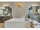 Modern bathroom with soaking tub, dual vanities, wood cabinets, and stylish lighting fixture at 4345 N Dapple Gray Rd, Las Vegas, NV 89129