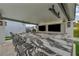 Elegant outdoor kitchen with marble counters, stainless steel appliances, sink, bar seating, and dual entertainment televisions at 4345 N Dapple Gray Rd, Las Vegas, NV 89129