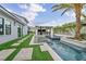 Backyard featuring a long pool with turf pavers, palm trees, and a covered outdoor kitchen, creating a resort-like setting at 4345 N Dapple Gray Rd, Las Vegas, NV 89129